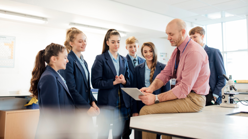 A teacher speaking to students standing around him
