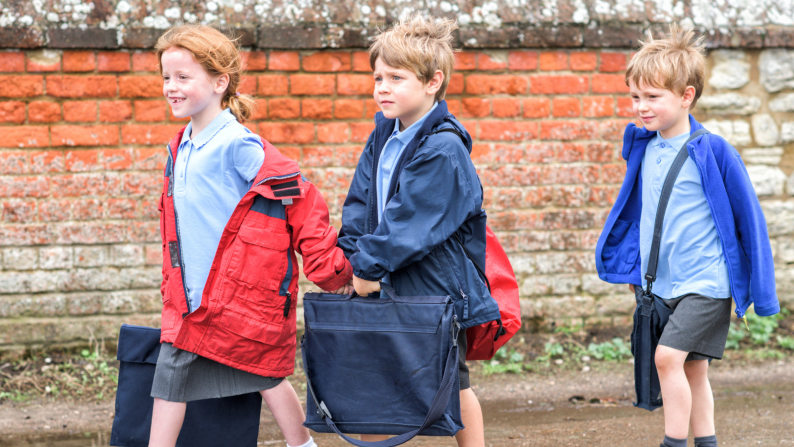 three young children walking to school in uniform
