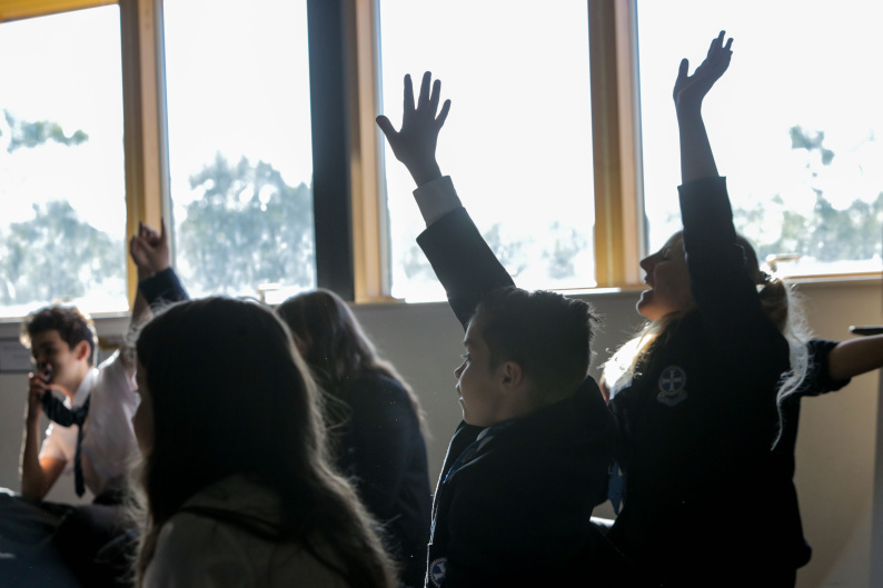 Photo of pupils with their hands up 