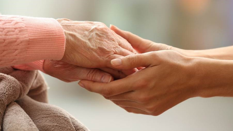 A pair of young hands holding an elderly hand