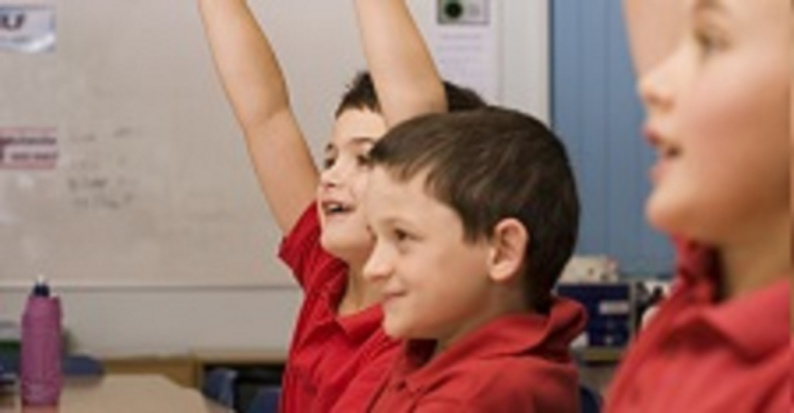 Children with hands raised in class